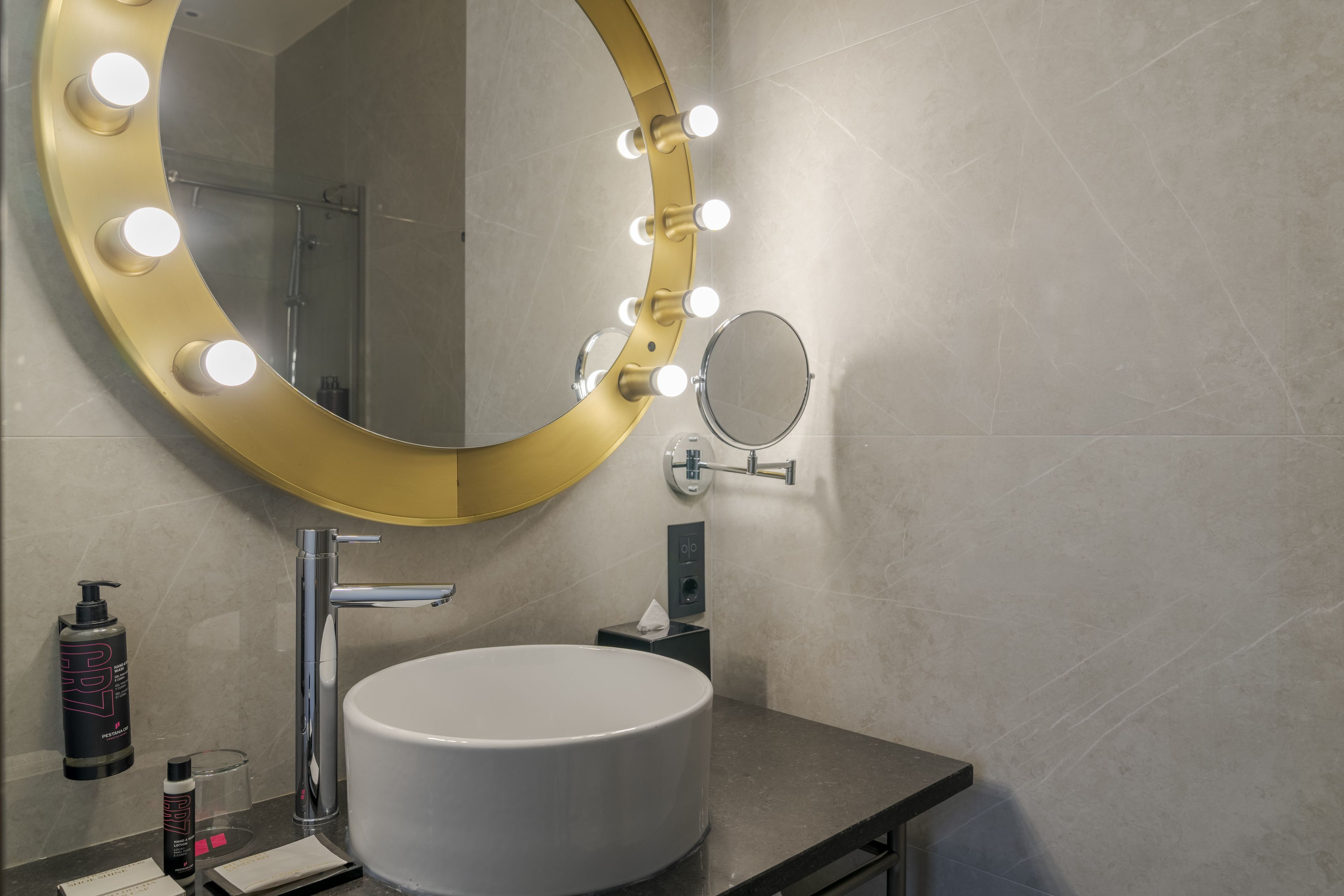 Un baño con tocador, lavamanos, espejo con iluminación y artículos de aseo.