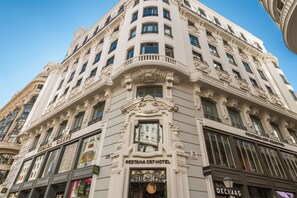 Un edificio histórico con detalles arquitectónicos ornamentales, incluyendo una entrada destacada y varias ventanas.