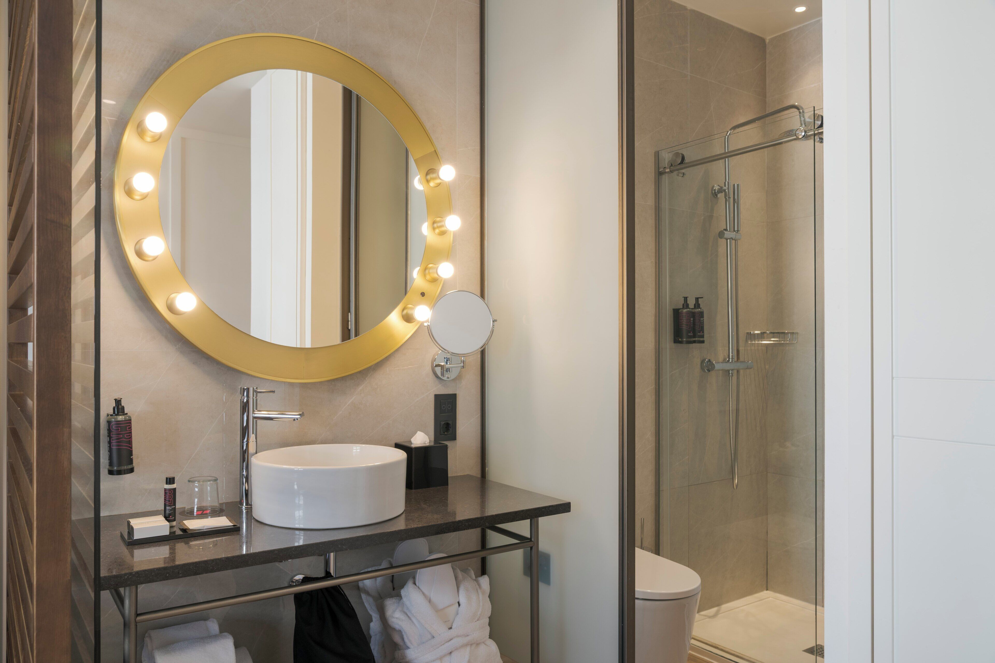 A modern bathroom with a large mirror, vanity, and a glass-enclosed shower.