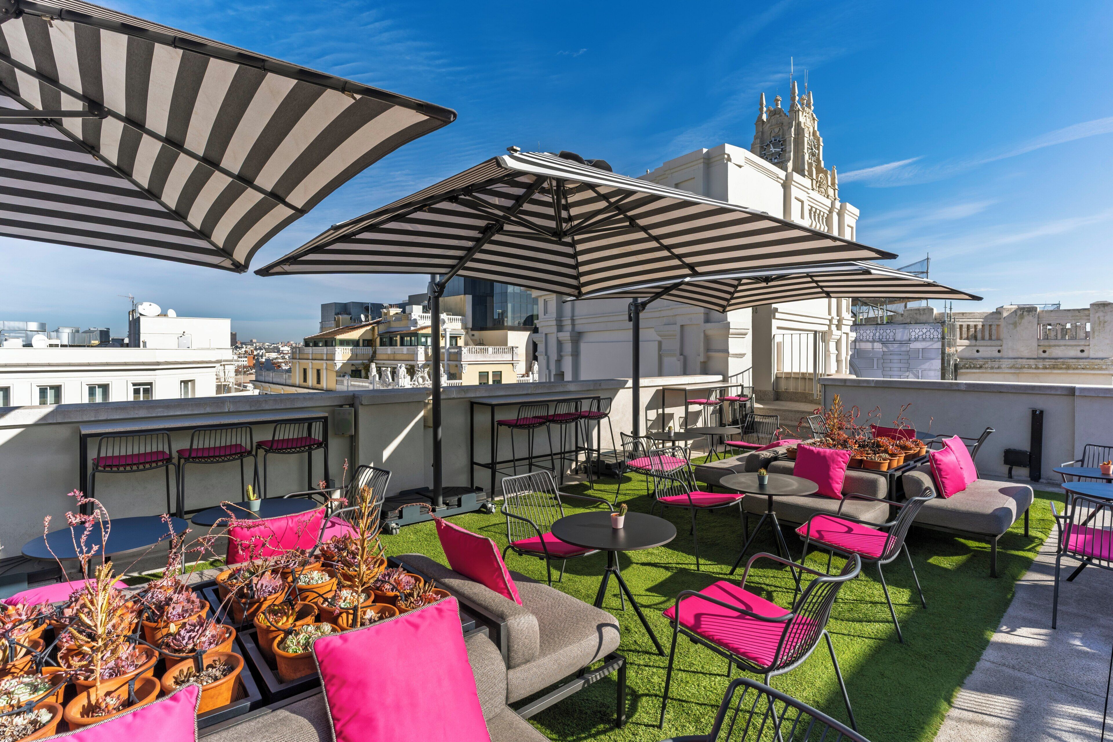 Terraza en la azotea con mobiliario exterior, sombrillas y plantas en macetas.