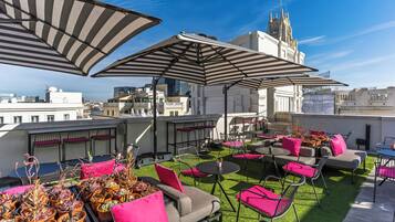 Terraza en la azotea con mobiliario exterior, sombrillas y plantas en macetas.