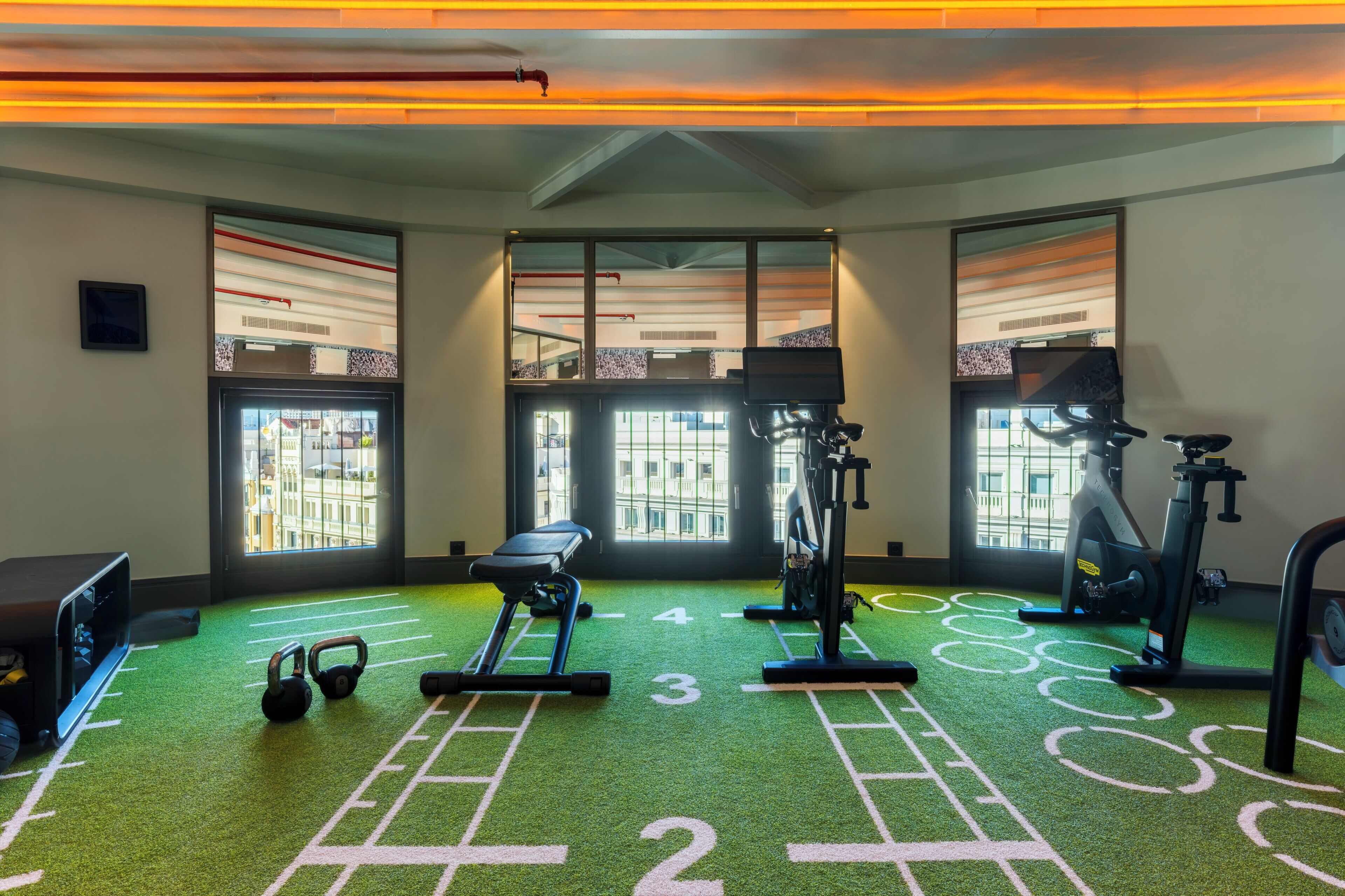 Una palestra con attrezzature per esercizi, tapis roulant e vogatore.