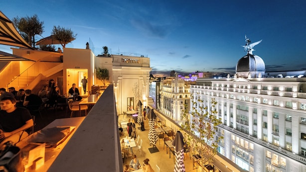 Eine Dachterrasse mit Außenplätzen, mit Blick auf ein historisches Gebäude mit einer Kuppel.