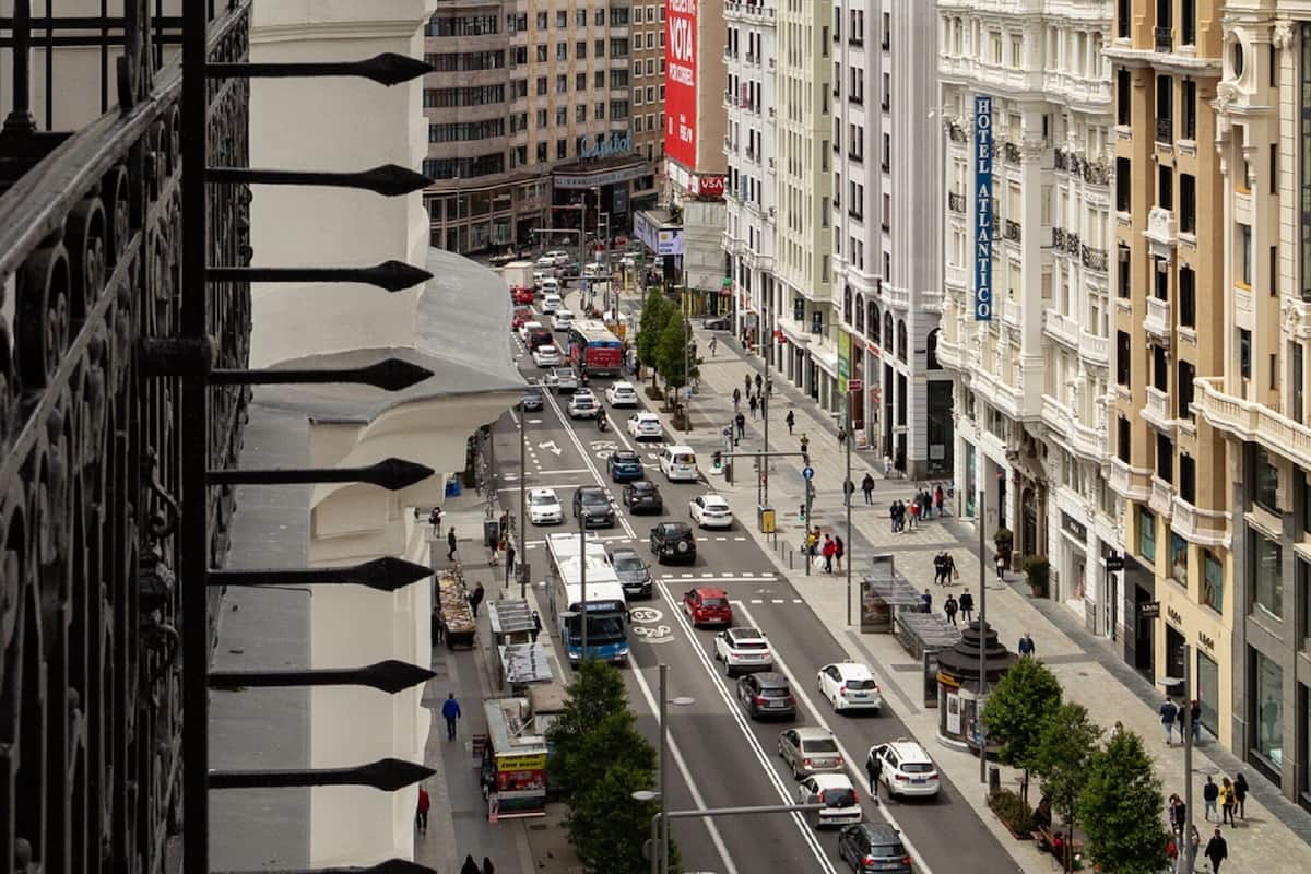 A busy urban street with historic buildings, a prominent red banner, and a clear view of the street from a high vantage point.