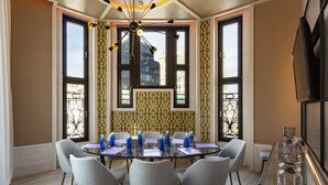 Une salle de conférence avec une table en verre, des chaises et un lustre.