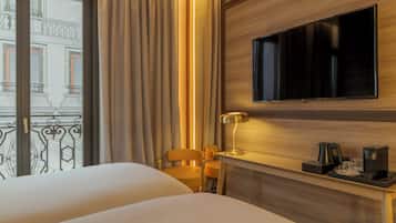 Ein Hotelzimmer mit einem Bett, einem an der Wand montierten Fernseher, einem Schreibtisch mit Lampe und einer Kaffeemaschine.