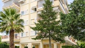 Ein mehrstöckiges Wohngebäude mit Balkonen, einem gepflasterten Gehweg und gepflegter Bepflanzung.
