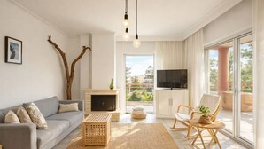 Ein modernes Wohnzimmer mit einer Couch, einem Kamin, einem Fernseher und einem Balkon mit Blick.