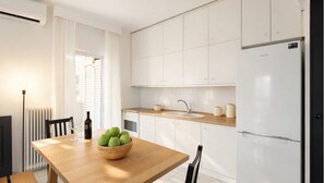 Eine moderne Küche mit weißen Schränken, einem Holztisch und einer Schüssel grüner Äpfel.