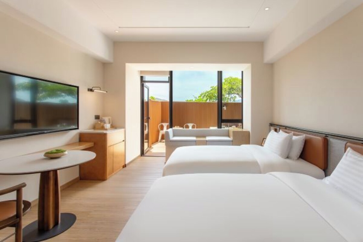 A modern hotel room with a large bed, a desk, and a TV.