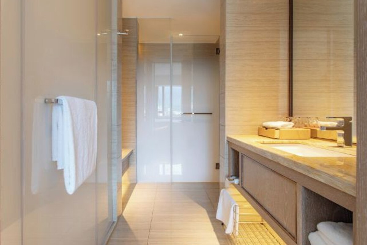 A modern bathroom with a glass shower enclosure, a wooden vanity, and a large mirror.