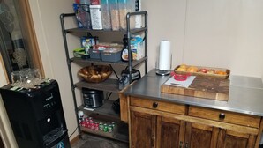 Una cocina con refrigerador, cafetera, panera y frutero.