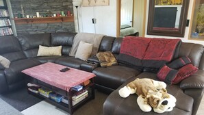 Una sala de estar con un sofá de cuero, una mesa de centro con juegos de mesa, un perro de peluche y un mapa mundial en la pared.