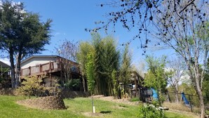 Una casa con balcón, rodeada de césped y árboles.