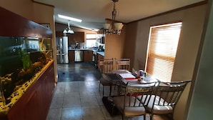 Una cocina con un acuario grande, una mesa de comedor con sillas y un refrigerador.