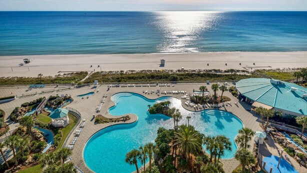A resort with multiple swimming pools, a beach, and a view of the ocean.