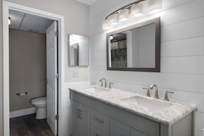 A bathroom with a double sink, a toilet, and a mirror. - Edgewater by iTrip Panama City Beach (Panama City Beach)