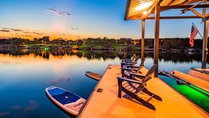 A calm lake with a dock, paddleboards, and chairs. - Private Boat Slip| Lakefront | Putting Green | Firepit (Burnet)