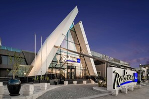 The Radisson Blu Hotel with a modern architectural design, featuring a prominent glass facade and a distinctive angular structure.