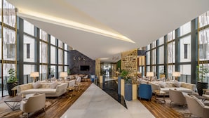 Un hall d’entrée spacieux avec un espace salon central, de grandes fenêtres et un décor moderne.