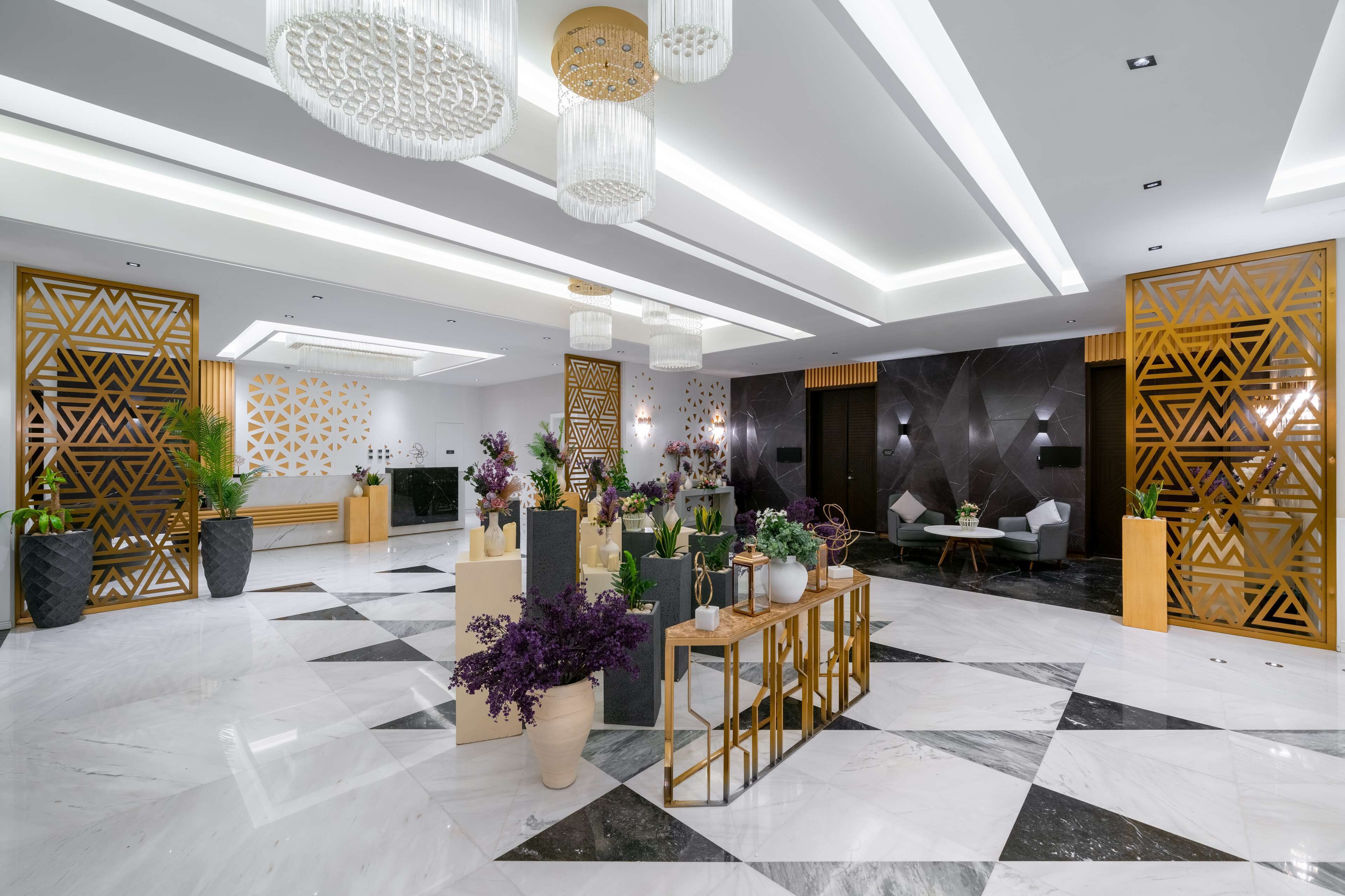 A spacious lobby with a checkered floor, decorative panels, and a central seating area with a table and chairs.