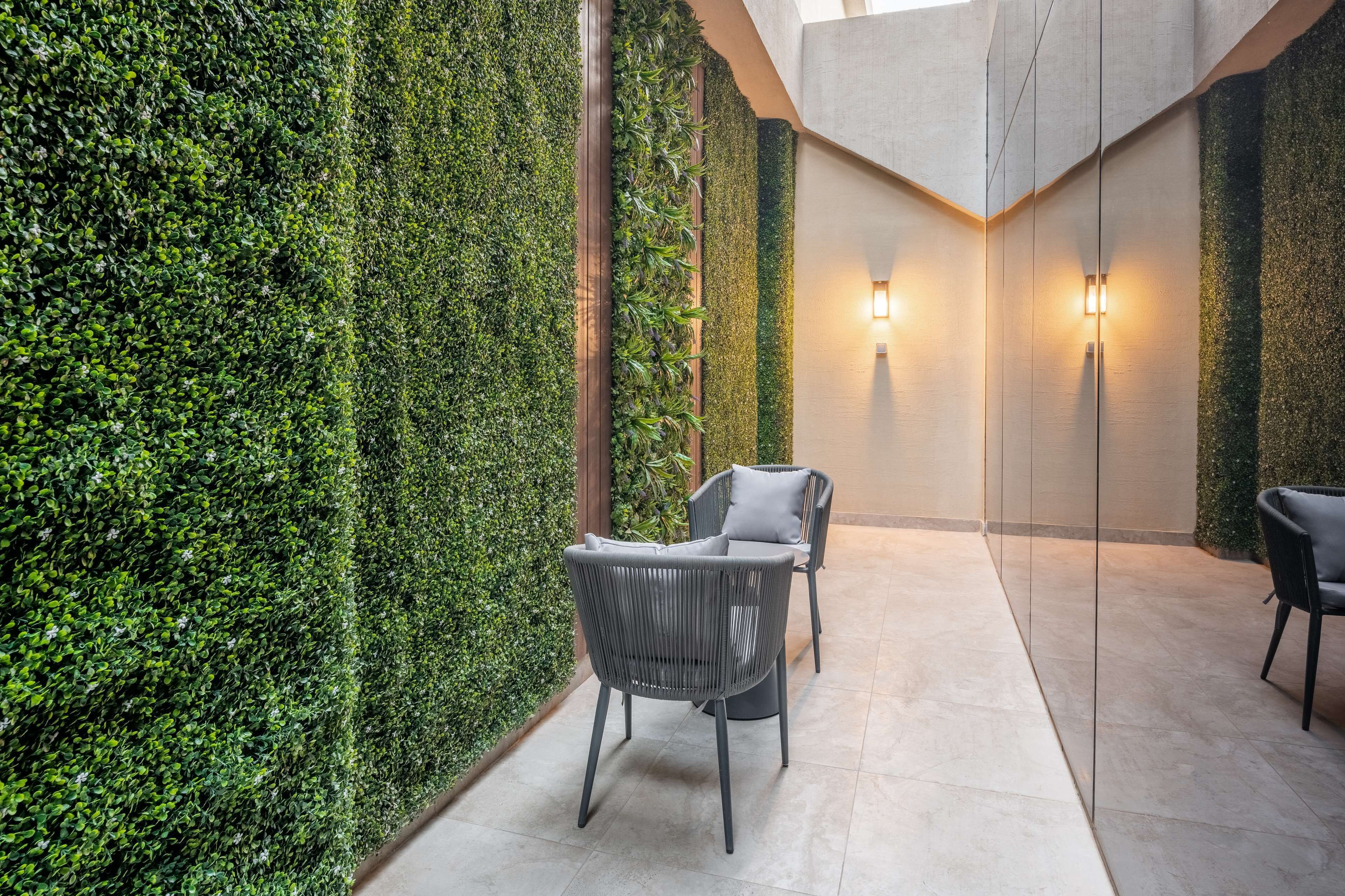 A modern indoor space with a green wall, two chairs, and a light fixture.