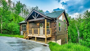 Une cabane en bois dotée d’un porche, entourée d’une végétation luxuriante.