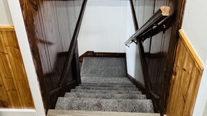 Una escalera de madera con un rellano alfombrado y un techo blanco.