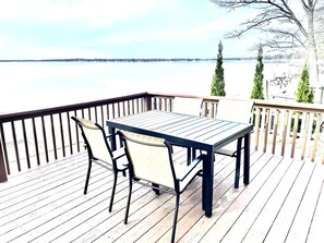 Une terrasse en bois avec une table et des chaises donnant sur une étendue d’eau.