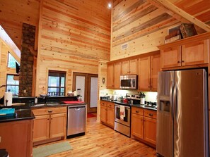 Una cocina amplia con armarios de madera, electrodomésticos de acero inoxidable y un pilar de piedra.