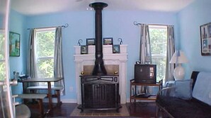 A cozy living room with a fireplace, a sofa, a coffee table, and a rug. - Tarheel Retreat (Henderson)