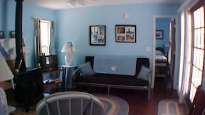 A room with a bed, a sofa, a chair, a lamp, and a ceiling fan. - Tarheel Retreat (Henderson)