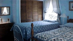 A bedroom with two single beds, wooden wardrobe, and a small bedside table with a lamp. - Tarheel Retreat (Henderson)