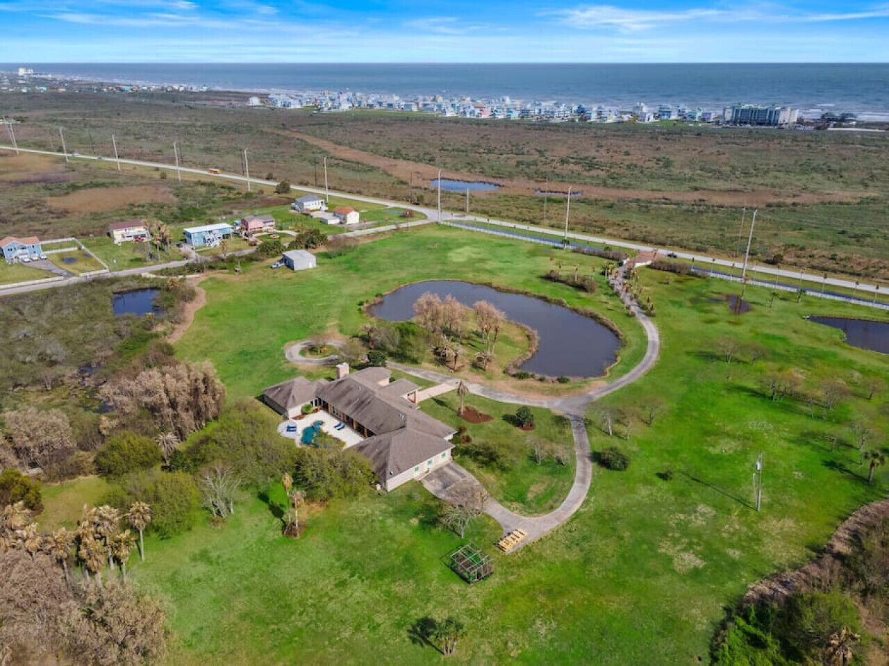 Luchtbeeld van een woongebied met huizen, een zwembad en een bochtige weg.