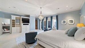 A bedroom with a large bed, built-in TV, storage cabinets, and a chandelier. - Luxurious Secluded Estate with Pool & Pond (Galveston)