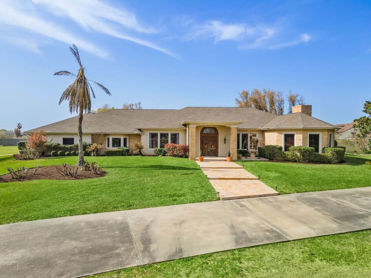 A single-story house with a front entrance, a driveway, and a well-maintained lawn.