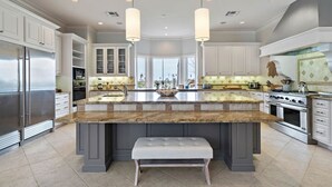 A spacious kitchen with granite countertops, stainless steel appliances, and pendant lighting. - Luxurious Secluded Estate with Pool & Pond (Galveston)