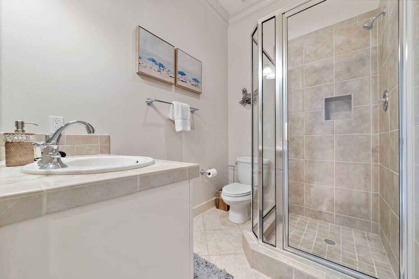 Un bagno moderno con doccia vetrata, lavabo con piano in marmo e water.