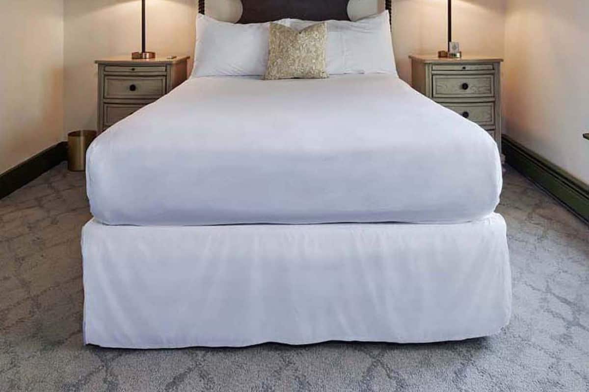 A large bed with a wooden headboard, two bedside tables, and a nightstand.