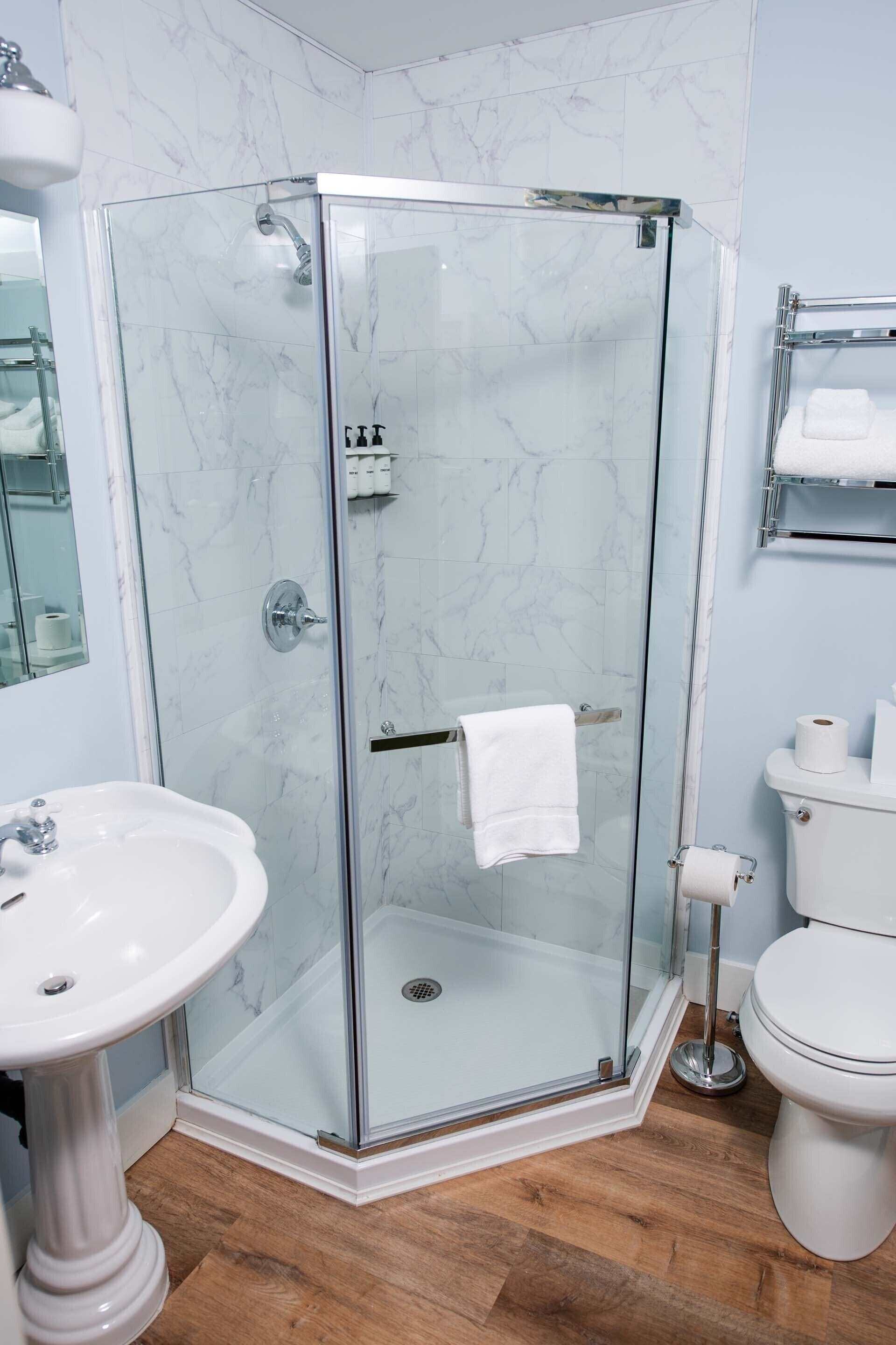Une salle de bain moderne avec une douche à parois de verre, un lavabo sur colonne et des toilettes.