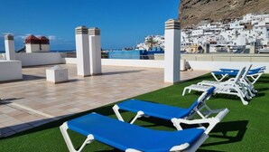 A rooftop pool area with blue lounge chairs and a view of a coastal town. - Junto A LA Playa, Magnifica Y Amplia Terraza EN Esquina (MOGAN)