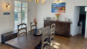 A dining area with a wooden table, chairs, pendant lights, a painting, and a cabinet with decorative items. - Villa for 8 people on the Gigaro beach (La Croix-Valmer)