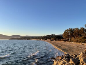 Una platja amb primer terme rocos, una riba sorrenca i un cel serè.