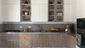 A modern kitchen with a gas stove, sink, and wooden cabinets. - Villa Azzura Lipari - Charm & Relax (Lipari)