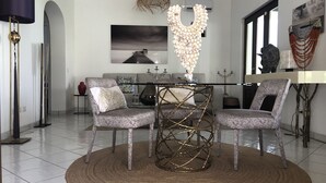 A modern living room with a round table, two chairs, a sofa, and a large painting on the wall. - Villa Azzura Lipari - Charm & Relax (Lipari)