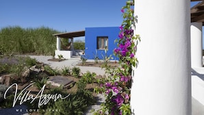 A modern villa with a blue exterior, surrounded by a landscaped garden with purple flowers and a clear blue sky. - Villa Azzura Lipari - Charm & Relax (Lipari)