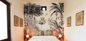 A hotel room with a bed, two nightstands, a window, and a tropical mural on the wall. - Villa Azzura Lipari - Charm & Relax (Lipari)