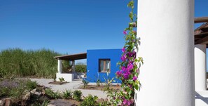 A modern villa with a blue exterior, surrounded by a landscaped garden with purple flowers and a clear blue sky. - Villa Azzura Lipari - Charm & Relax (Lipari)