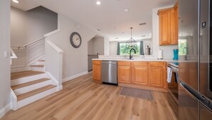 A modern kitchen with wooden cabinets, a stainless steel dishwasher, and a large refrigerator. - Vista Cay Luxury Villa- Allergy Free. Walk to Epic Universe and the OCCC (Orlando)