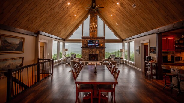 A spacious dining area with a high ceiling and a stone fireplace. - Luxury Lodge with Ride-In-Ride-Out Location - WiFi - Sweeping Mountain Views (Huntsville)